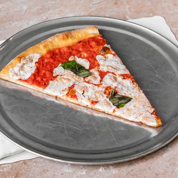A single slice of pizza with red sauce, white cheese, and basil on a metal tray.